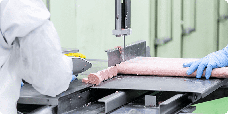 サイコロステーキを加工している機械と従業員の後ろ姿
