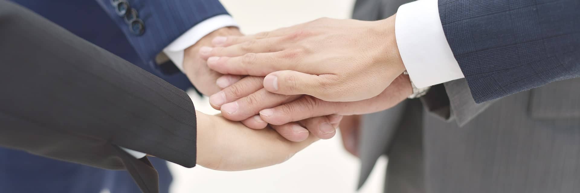 サラリーマン2人が重ねている手のアップ
