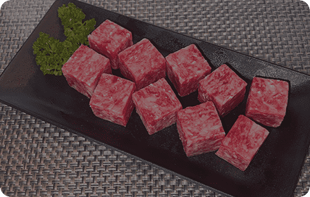 黒い皿の上に置かれる加工前のサイコロ型ステーキ